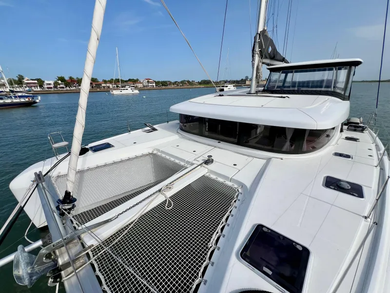 Slide: The Image of 2024 Lagoon 42 catamaran on calm water, showcasing sleek design and spacious deck. - 10