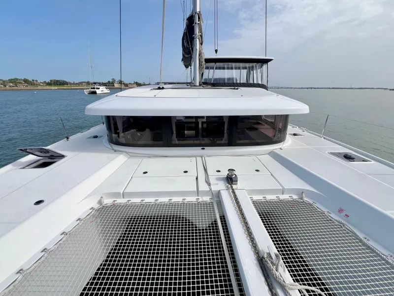 Slide: The Image of 2024 Lagoon 42 catamaran on calm water, showcasing sleek design and spacious deck. - 12