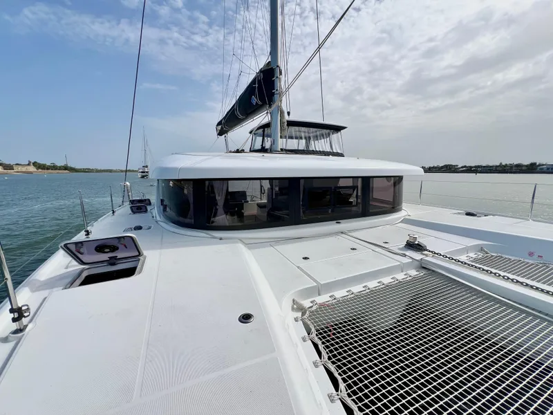 Slide: The Image of 2024 Lagoon 42 catamaran on calm water, showcasing sleek deck and modern design. - 14