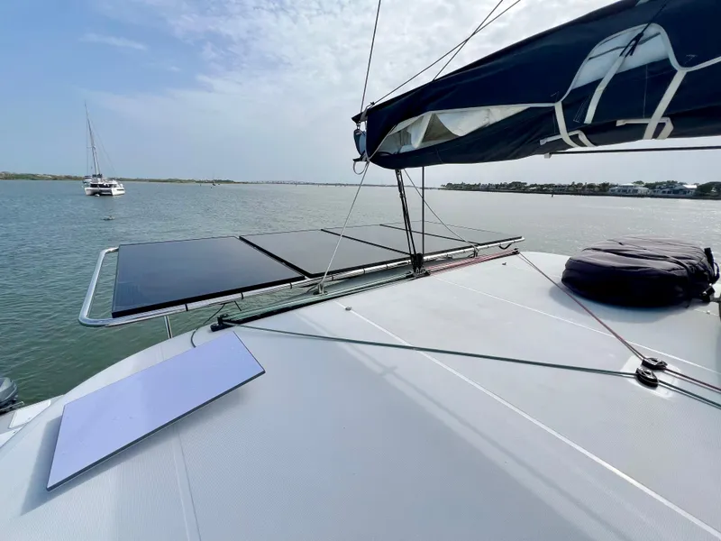 Slide: The Image of 2024 Lagoon 42 catamaran with solar panels on deck, sailing in calm waters. - 17