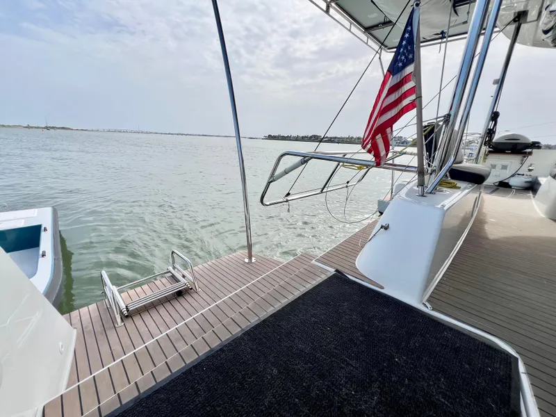 Slide: The Image of 2024 Lagoon 42 catamaran deck with American flag, overlooking calm waters. - 21