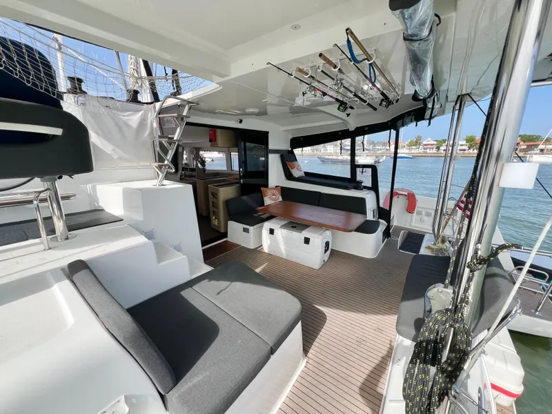 Slide: The Image of 2024 Lagoon 42 catamaran interior with modern seating, fishing rods, and waterfront view. - 24