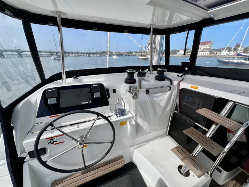 Slide: The Image of 2024 Lagoon 42 yacht cockpit with steering wheel, navigation equipment, and marina view. - 29