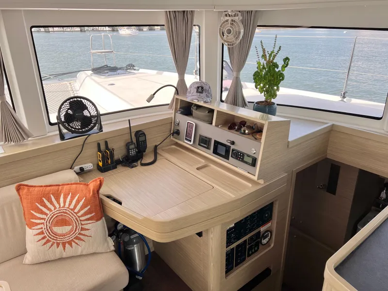 Slide: The Image of 2024 Lagoon 42 yacht interior with navigation station, fan, and decorative pillow. - 43