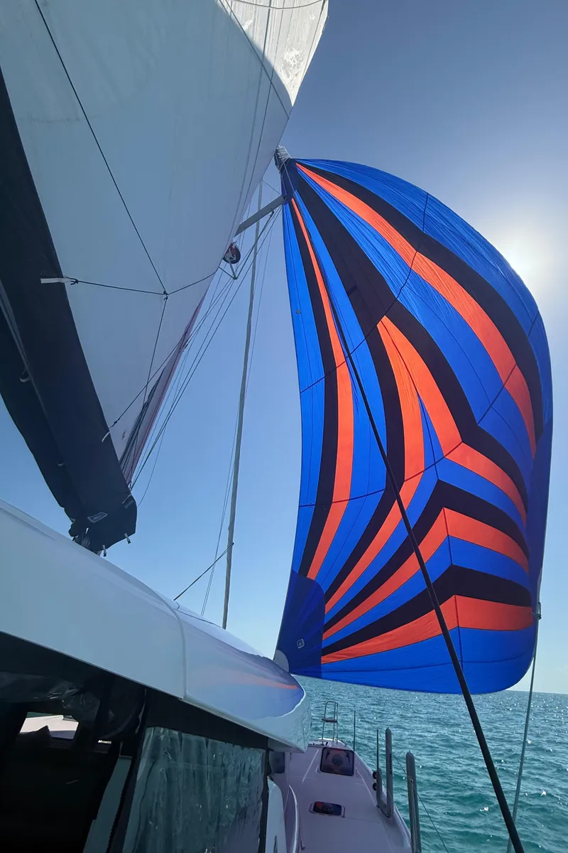 Slide: The Image of 2024 Lagoon 42 catamaran with vibrant blue and orange sail on open sea. - 5