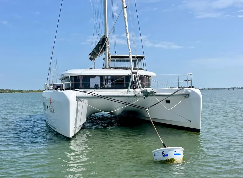 Slide: The Image of 2024 Lagoon 42 catamaran anchored in calm waters under a clear blue sky. - 7