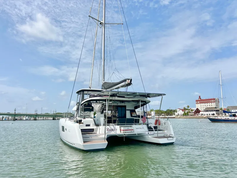 Slide: The Image of 2024 Lagoon 42 catamaran anchored in a scenic harbor with clear skies. - 9