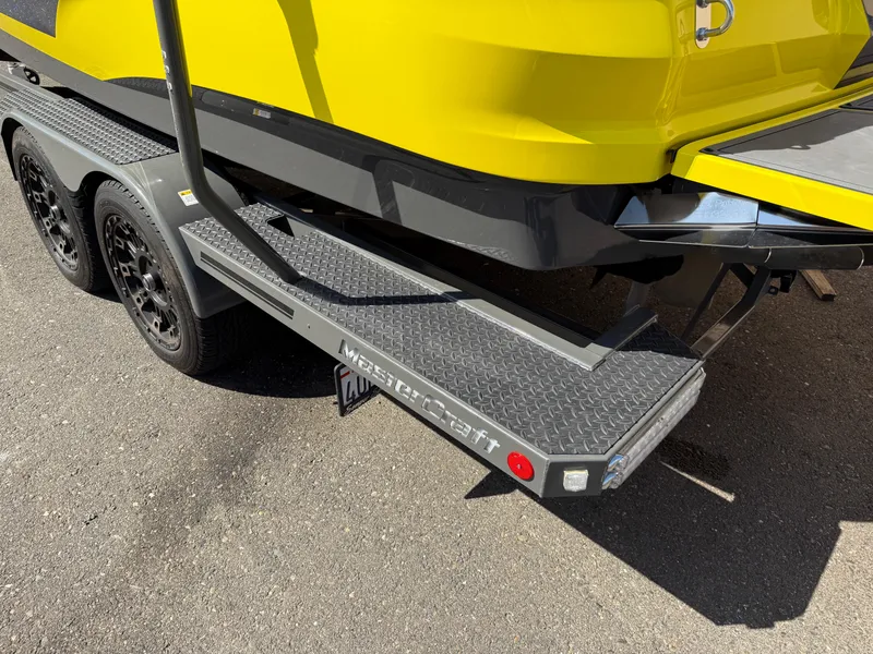 Slide: The Image of 2019 MasterCraft X22 boat trailer with yellow hull and black wheels. - 10