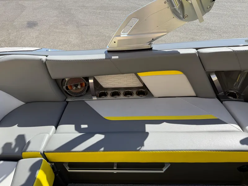 Slide: The Image of 2019 MasterCraft X22 boat interior with gray and yellow seating, speaker, and cup holders. - 22