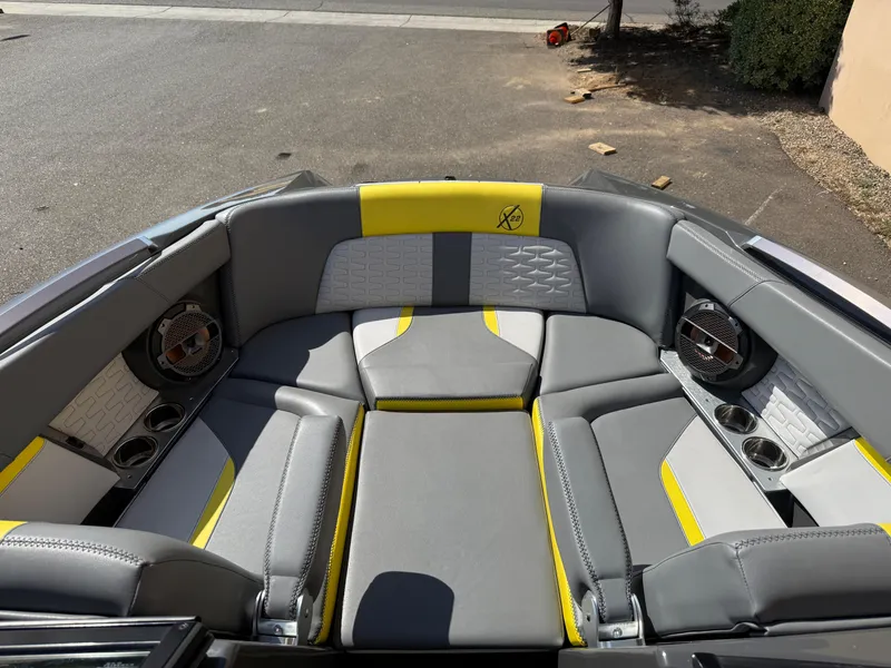 Slide: The Image of 2019 MasterCraft X22 boat interior with gray and yellow seating, featuring built-in speakers. - 26