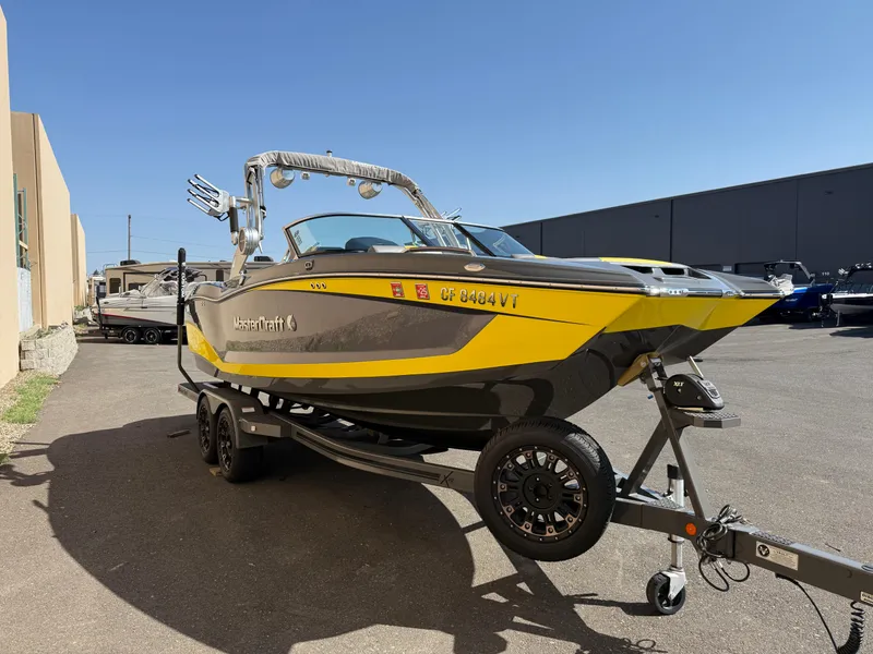 Slide: The Image of 2019 MasterCraft X22 boat in yellow and black on a trailer, parked outdoors. - 5
