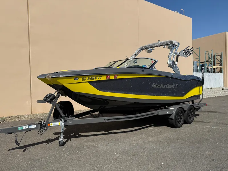 Slide: The Image of 2019 MasterCraft X22 boat in yellow and black on a trailer, parked outdoors. - 7