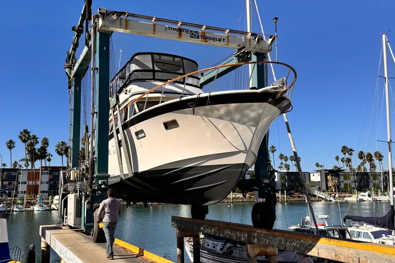 The Image of 1988 Overseas PT52 Cockpit Motoryacht lifted at marina, clear blue sky, palm trees in background. - 0