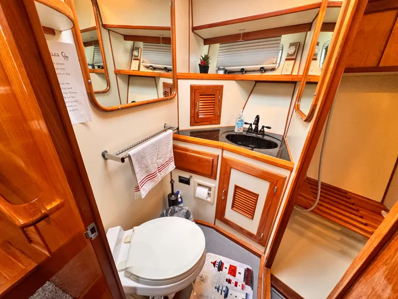Slide: The Image of 1988 Overseas PT52 Cockpit Motoryacht bathroom with wooden cabinetry, sink, and toilet. - 11
