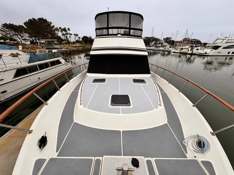 Slide: The Image of 1988 Overseas PT52 Cockpit Motoryacht docked in a marina, showcasing spacious deck and sleek design. - 26