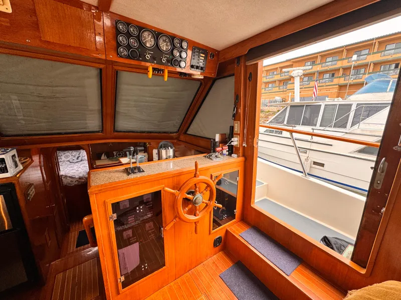 Slide: The Image of 1988 Overseas PT52 Cockpit Motoryacht interior with wooden helm, gauges, and marina view. - 3