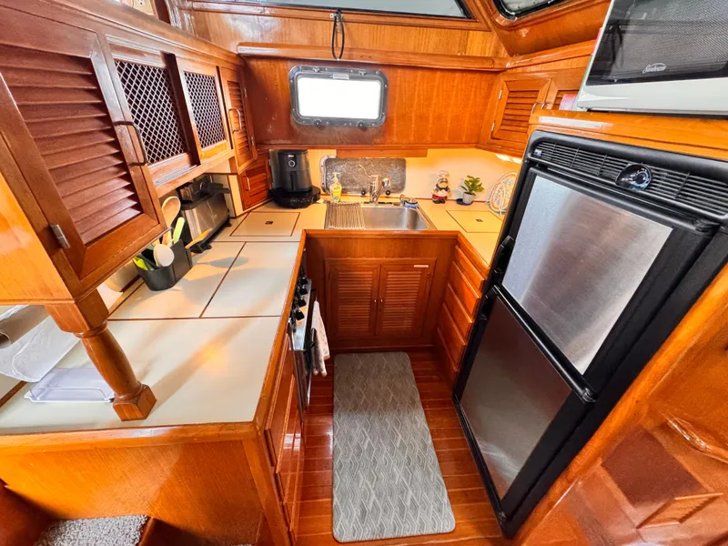 Slide: The Image of 1988 Overseas PT52 Cockpit Motoryacht kitchen with wood cabinetry, stainless steel appliances, and compact design. - 8