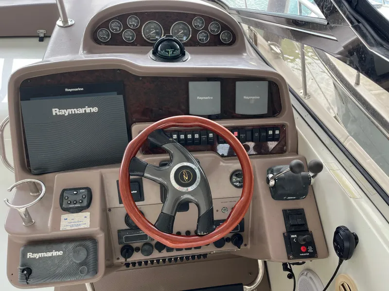 Slide: The Image of 2004 Regal Commodore 4260 helm with Raymarine navigation and wood-accented steering wheel. - 19