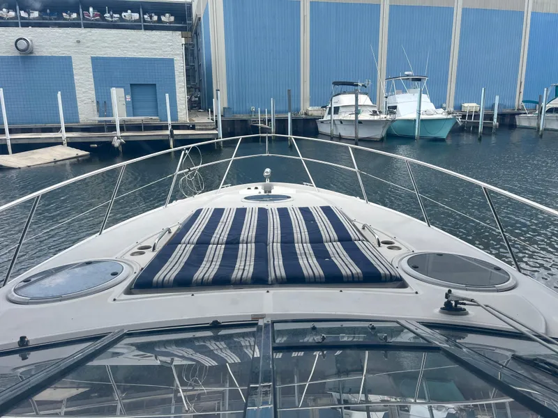 Slide: The Image of 2004 Regal Commodore 4260 yacht docked at marina, featuring striped sun pad and sleek design. - 30