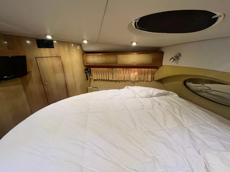 Slide: The Image of Interior cabin of 2004 Regal Commodore 4260 yacht with bed, TV, and storage cabinets. - 42