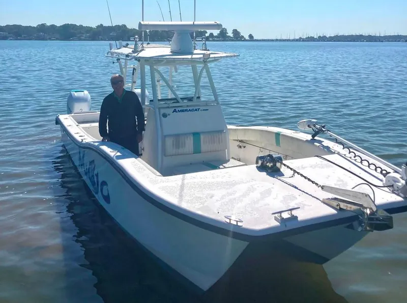 Slide: The Image of 2015 AmeraCat 27 boat on calm water with a person standing onboard. - 2