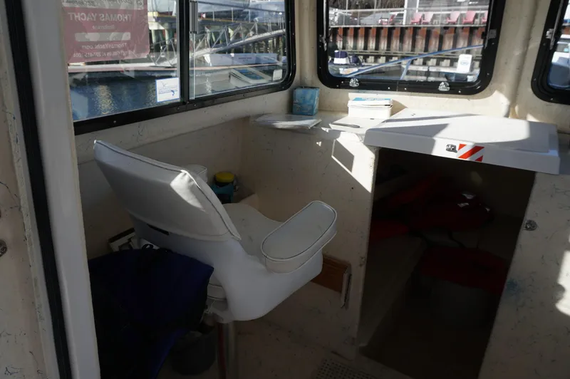Slide: The Image of Interior of 2005 Privateer 2400 boat with white captain's chair and windows. - 10