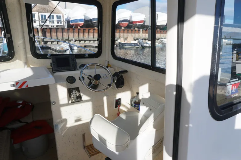 Slide: The Image of Interior of a 2005 Privateer 2400 boat, featuring steering wheel and navigation equipment. - 8