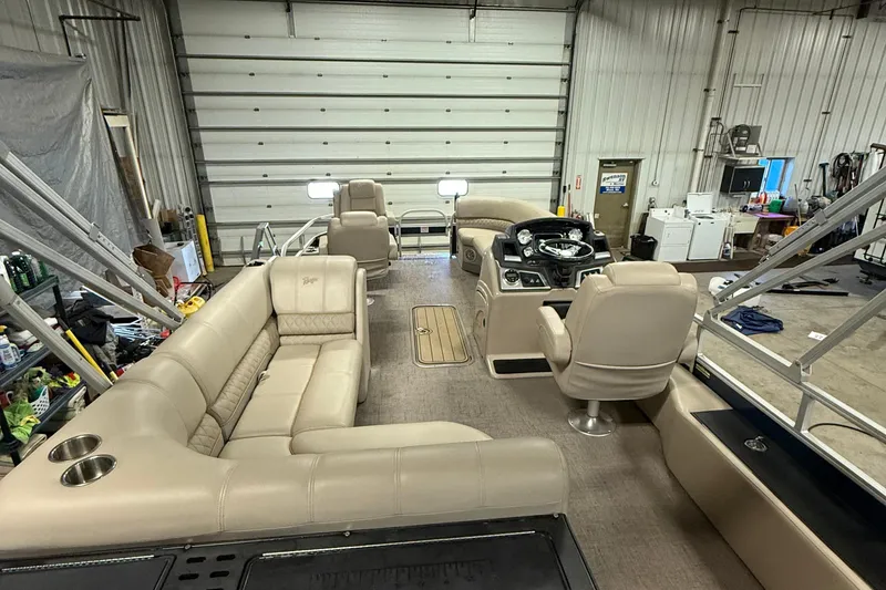 Slide: The Image of 2021 Ranger 223FC pontoon boat interior with beige seating in a garage setting. - 12