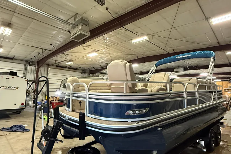 Slide: The Image of 2021 Ranger 223FC pontoon boat in a spacious indoor storage facility. - 2