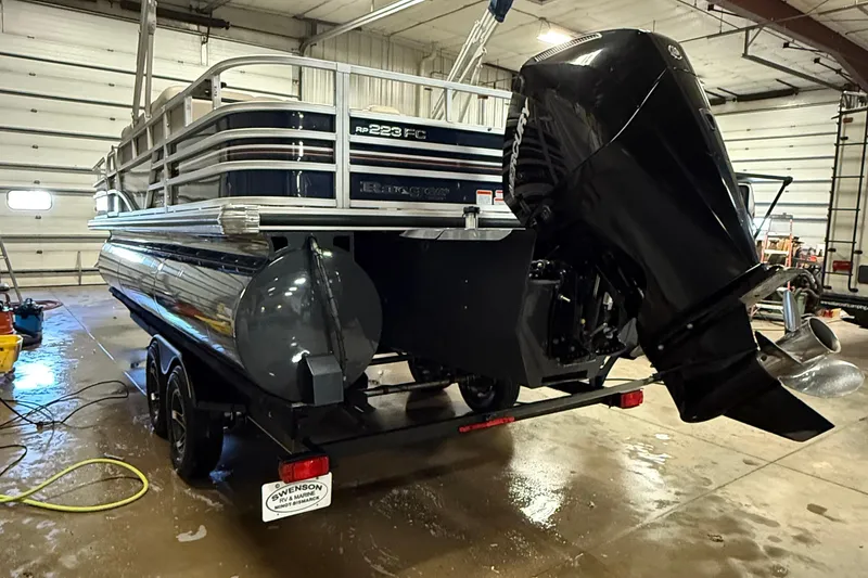 Slide: The Image of 2021 Ranger 223FC pontoon boat in a garage, featuring a powerful outboard motor. - 3
