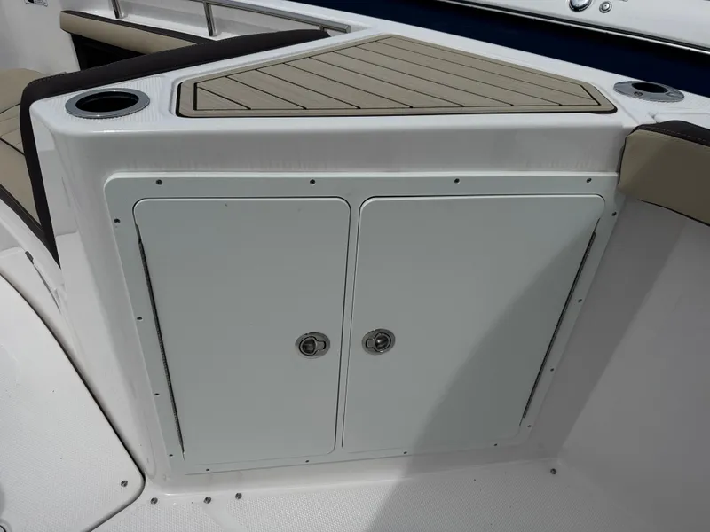 Slide: The Image of 2025 Yamaha Boats 255 FSH Sport E storage compartment with cup holders and cushioned seating. - 14