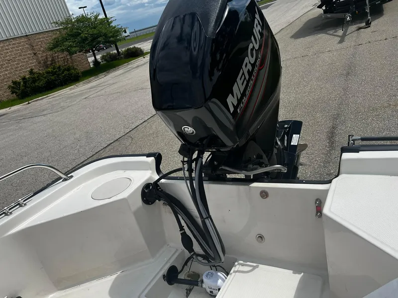 Slide: The Image of 2016 Boston Whaler 150 Montauk boat with Mercury outboard motor, parked on a paved area. - 15