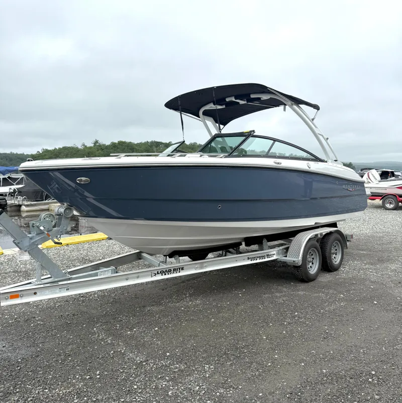 Slide: The Image of 2025 Monterey 238 Super Sport boat on trailer, blue hull, parked outdoors. - 1
