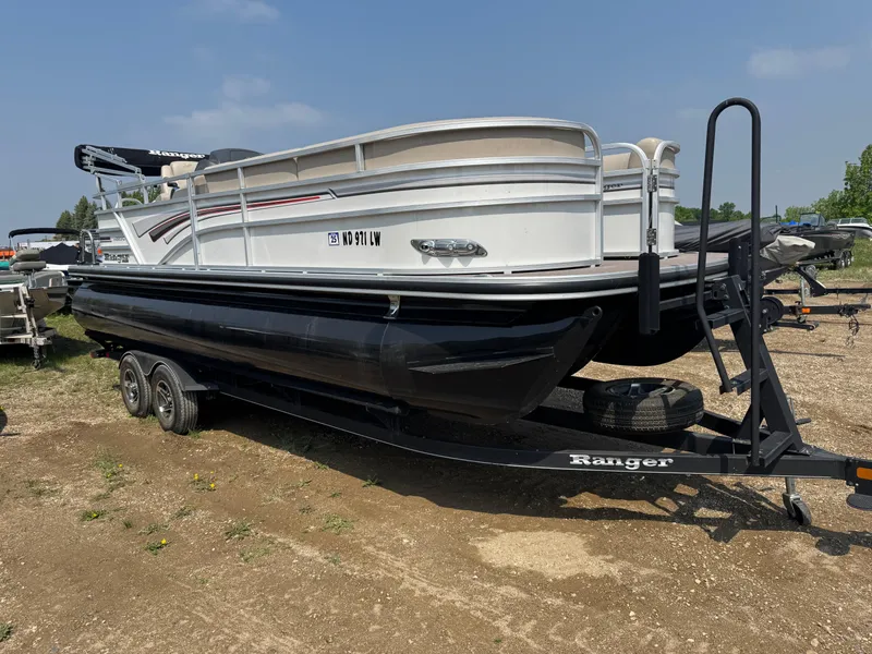 Slide: The Image of 2020 Ranger Reata 223C pontoon boat on trailer, parked outdoors. - 2