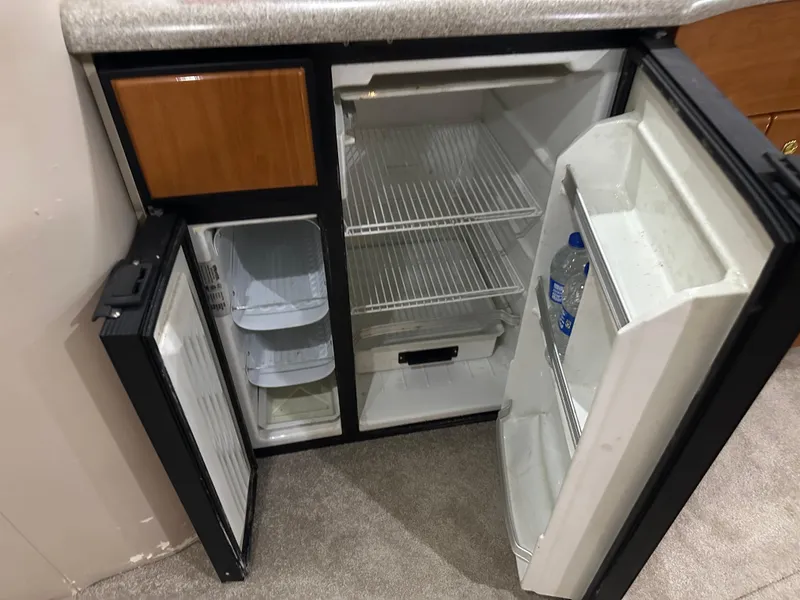 Slide: The Image of Open mini fridge in a 2000 Formula 40 PC boat, showing empty shelves and a water bottle. - 42