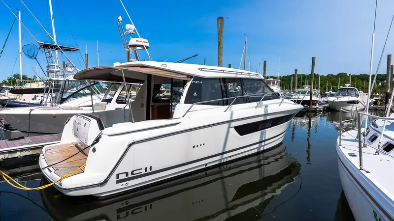 Slide: The Image of 2018 Jeanneau NC11 yacht docked in a marina under clear blue skies. - 1