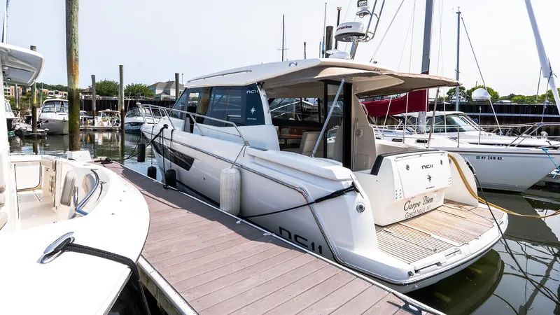 Slide: The Image of 2018 Jeanneau NC11 yacht docked at marina, showcasing sleek design and modern features. - 2