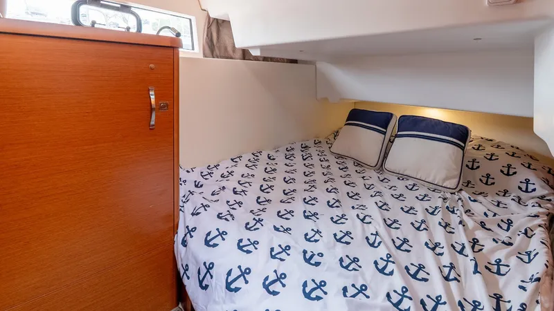 Slide: The Image of Cozy cabin interior of 2018 Jeanneau NC11 with anchor-patterned bedding and wooden cabinet. - 33