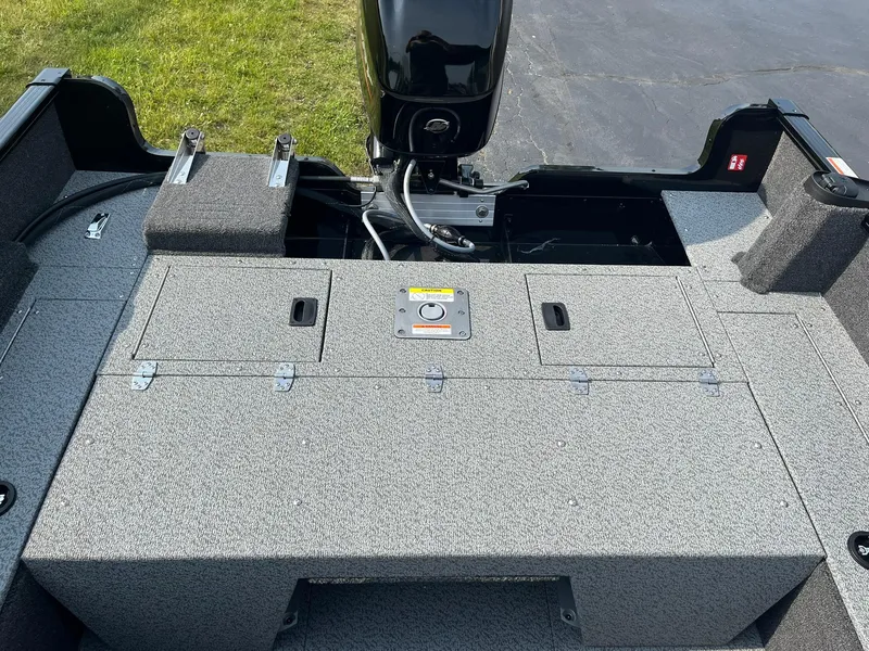 Slide: The Image of 2026 Lund 1650 Rebel XL SS boat interior with motor, gray deck, and storage compartments. - 8