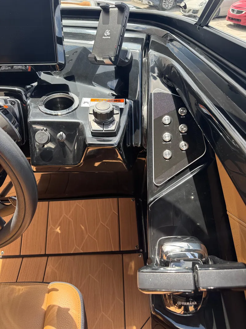 Slide: The Image of 2025 Yamaha Boats 255XD dashboard with controls, cup holder, and phone mount. - 27