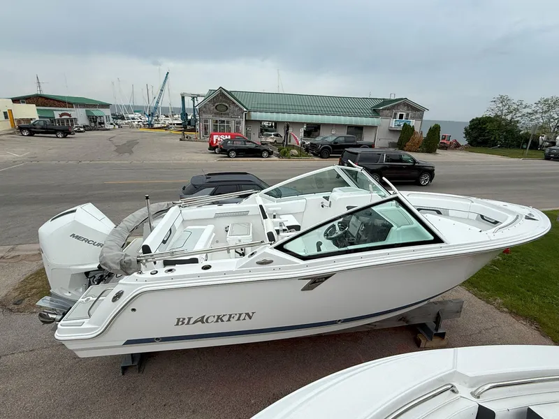 The Image of 2026 Blackfin 232 DC boat on display at a marina, featuring a sleek white design. - 0