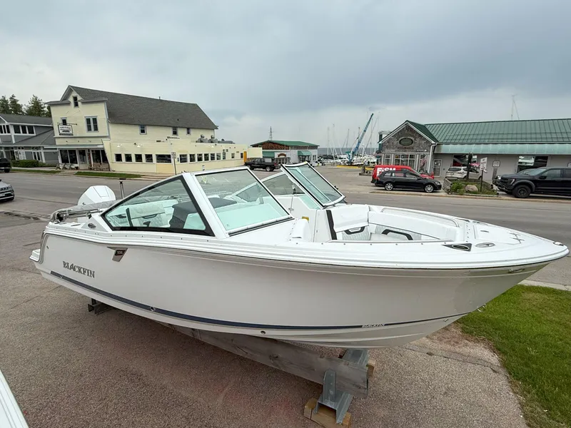 Slide: The Image of 2026 Blackfin 232 DC boat displayed outdoors near marina and buildings. - 2