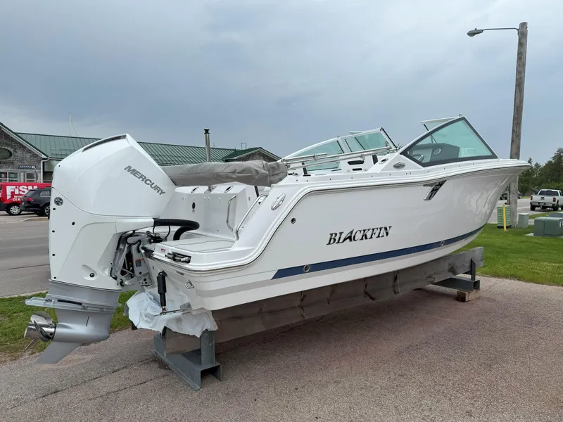 Slide: The Image of 2026 Blackfin 232 DC boat with Mercury engine, displayed outdoors on a stand. - 25