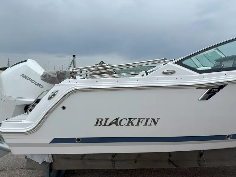 Slide: The Image of 2026 Blackfin 232 DC boat with Mercury engine, docked under cloudy skies. - 26