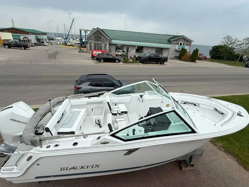 Slide: The Image of 2026 Blackfin 232 DC boat on display near a marina with overcast skies. - 3