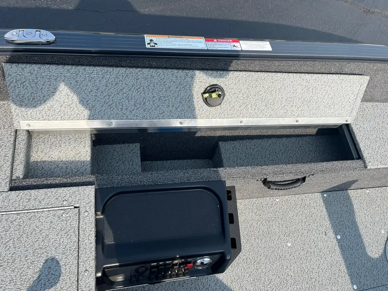 Slide: The Image of 2026 Lund 1650 Rebel XL Tiller boat storage compartment with open lid and control panel. - 18