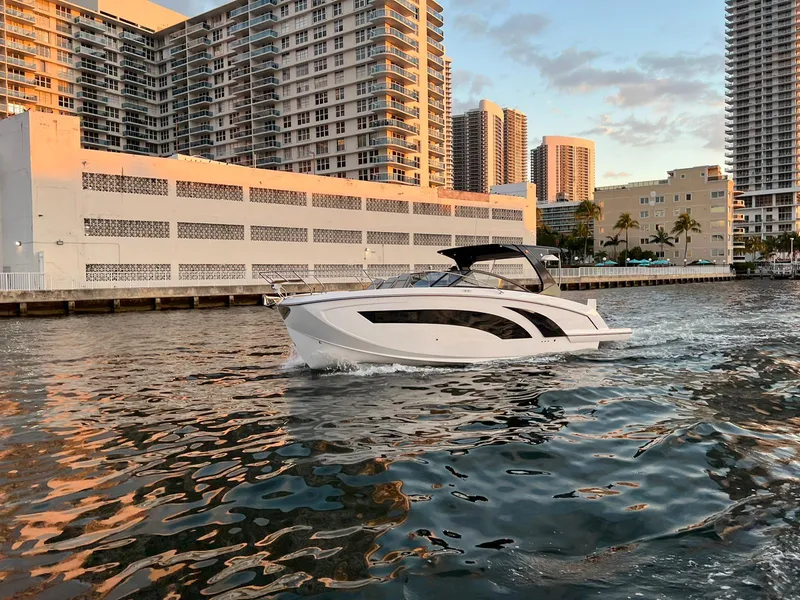 Slide: The Image of 2023 Hanover 377 boat cruising near urban waterfront buildings at sunset. - 2