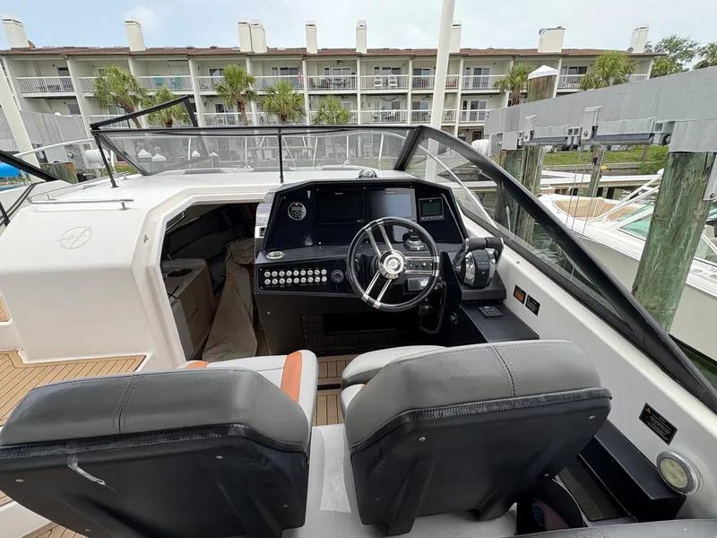 Slide: The Image of 2023 Hanover 377 boat cockpit with modern steering and controls, docked near waterfront buildings. - 25