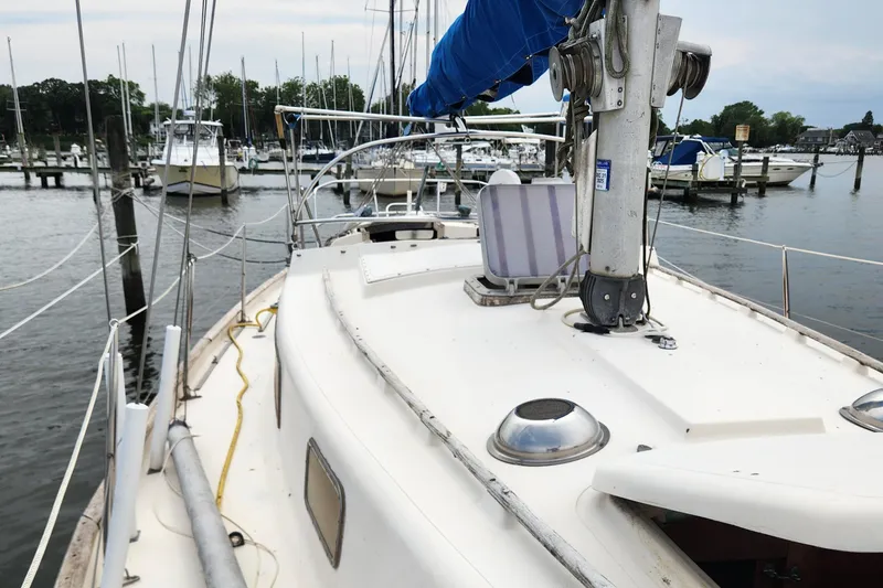 Slide: The Image of 1974 Hallberg-Rassy Rasmus 35 sailboat docked in a marina, featuring a clean deck and blue sail cover. - 11
