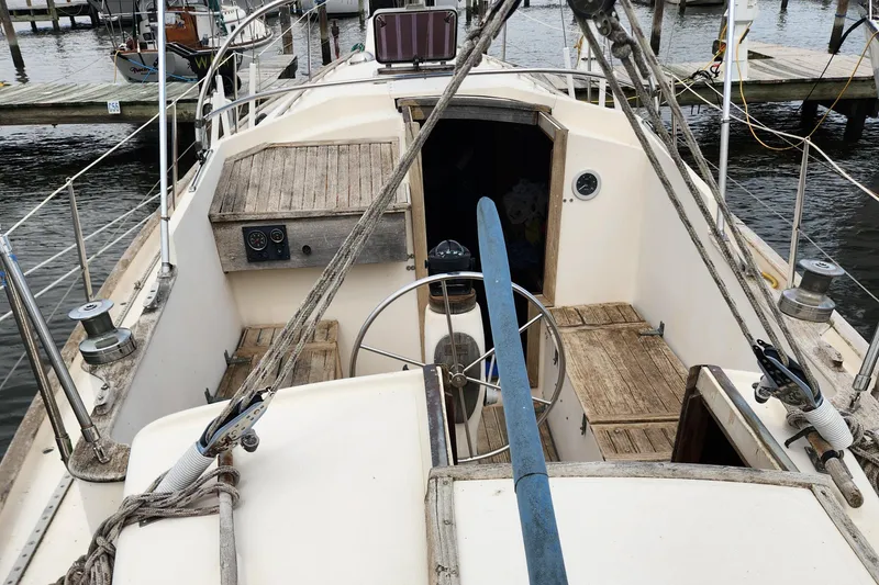 Slide: The Image of 1974 Hallberg-Rassy Rasmus 35 sailboat cockpit with wooden seating and steering wheel. - 23
